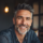 Homme souriant avec barbe grise, ambiance chaleureuse.