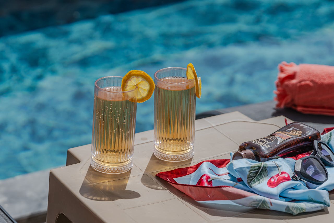 Two lemon cocktails on a sunny poolside table, perfect for summer relaxation.